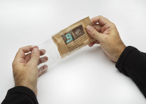 Hand removing 49% RH Boveda from the plastic wrapper